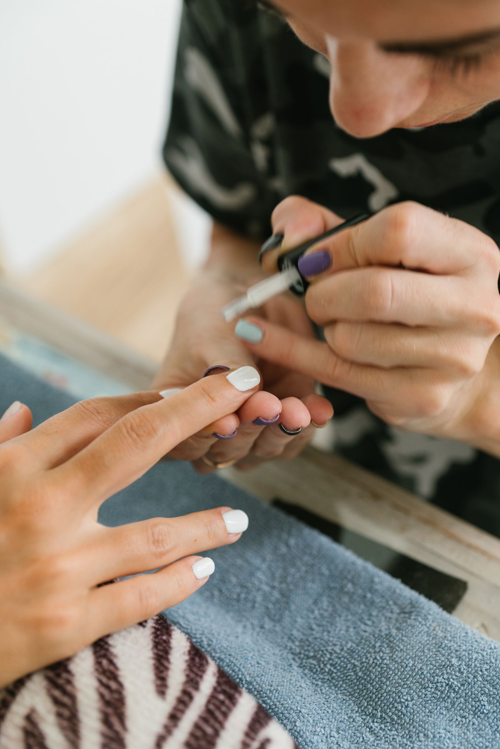Nail technician painting a client’s fingernails
